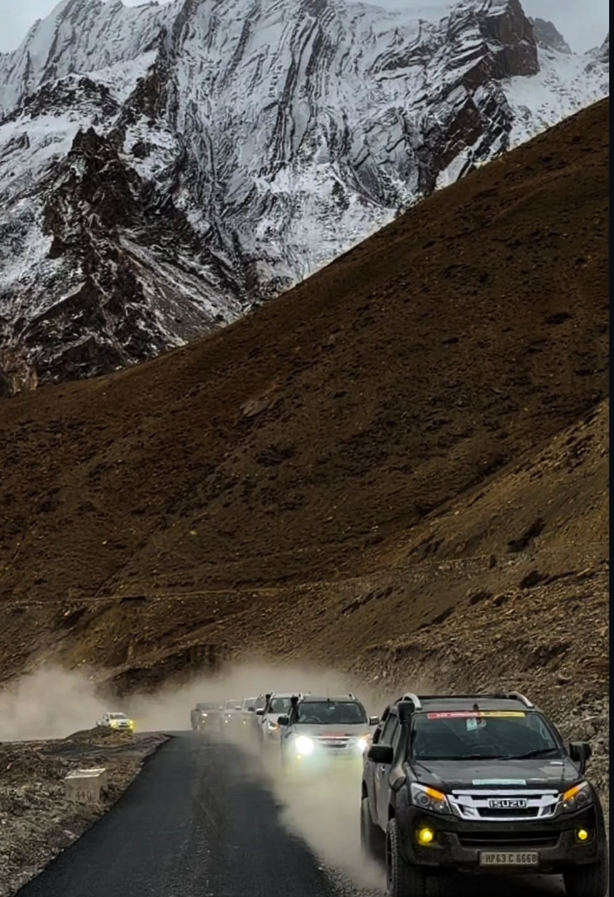Convoy of expedition SUVs lined up on a high Himalayan pass